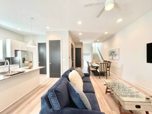 Una sala de estar moderna con un sofá, una mesa de centro de vidrio y un comedor con una mesa y sillas.