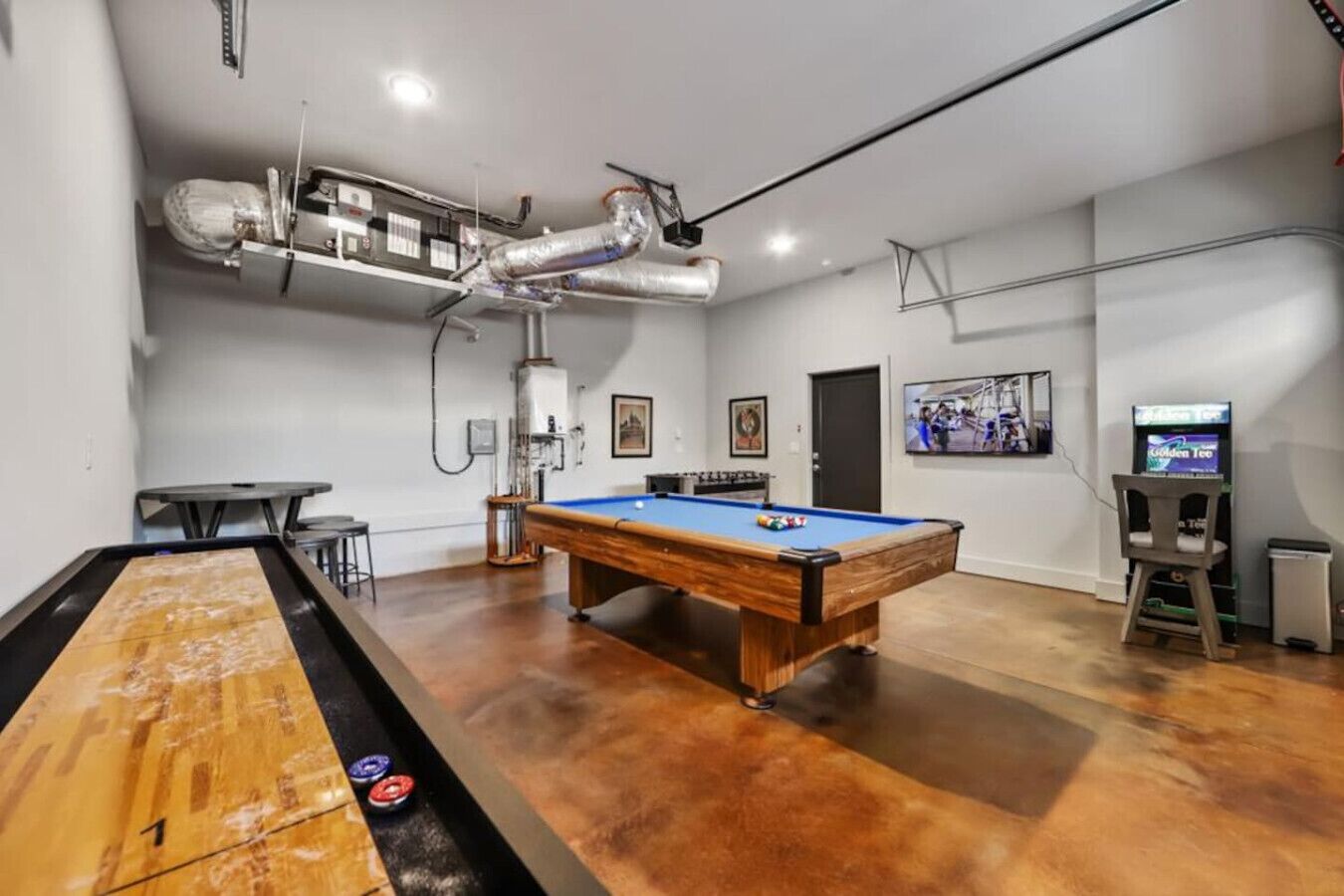 A billiards room with a pool table, a foosball table, and a television.