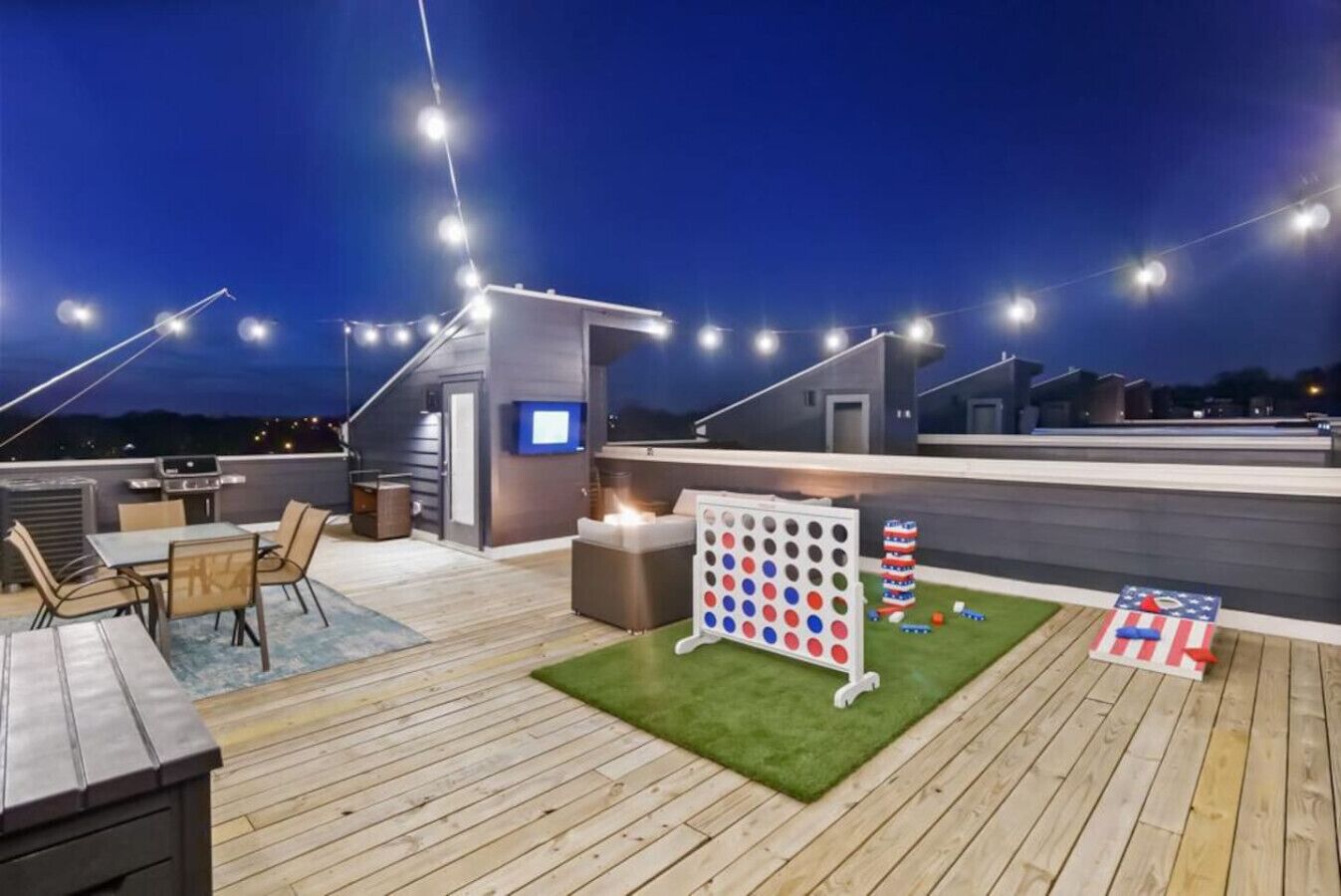 A rooftop deck with a grill, seating area, and a game table.