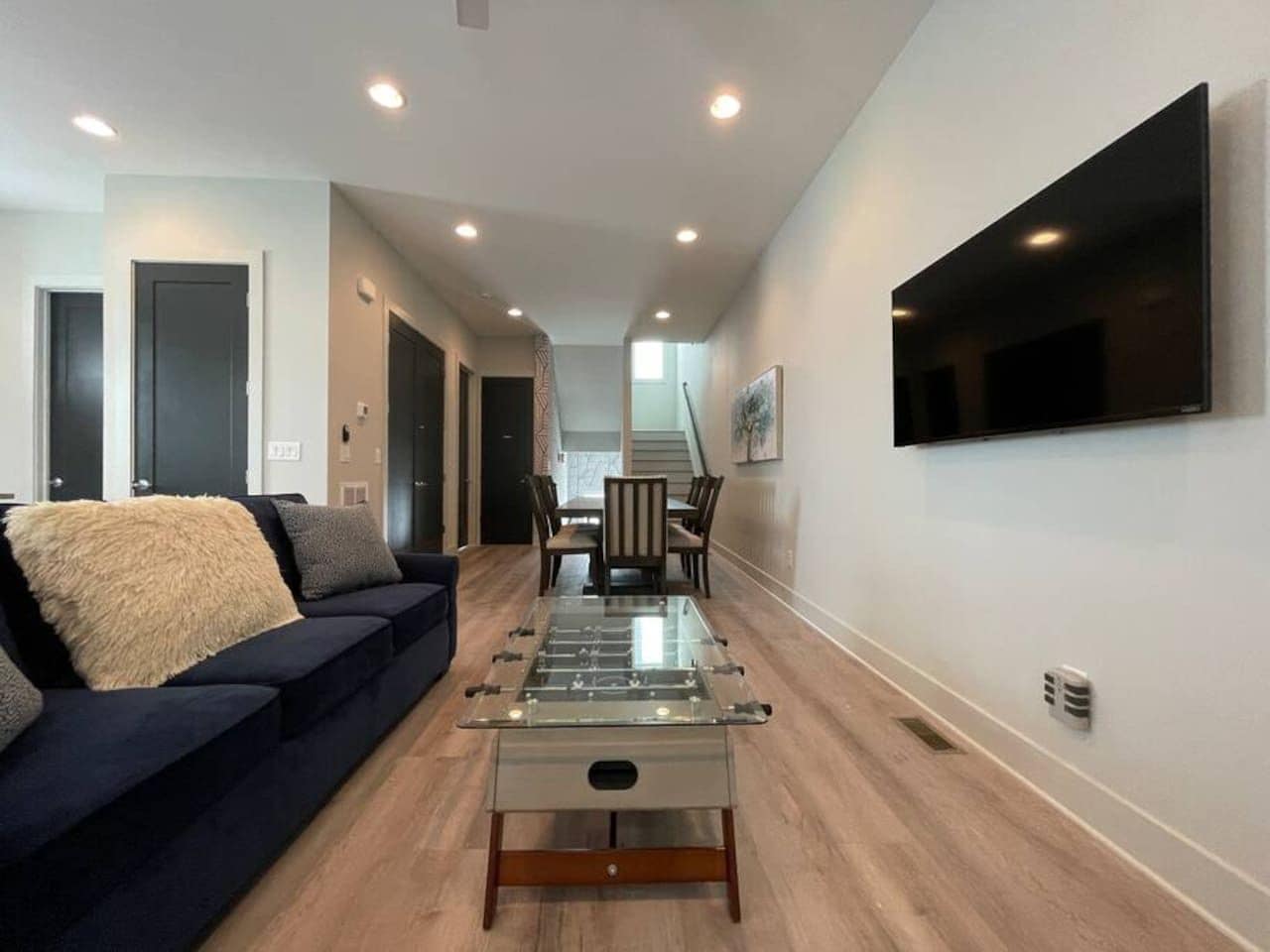 Una sala de estar moderna con un sofá, una mesa de centro de vidrio y un televisor de pantalla plana montado en la pared.