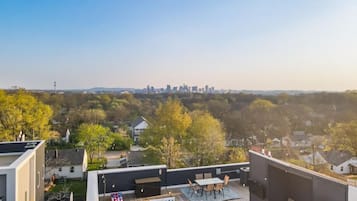 Terraza en la azotea con vistas al horizonte urbano, un pequeño jardín y mobiliario exterior.