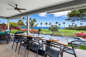 Ett takförsett utomhusområde där man kan äta med utsikt över havet och en golfbana.