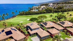 A residential area with houses featuring solar panels, a golf course, and a view of the ocean. - Holua Kai #26: Luxury Fairway Front Villa w/ Pool, Spa, Lanai, AC & Ocean Views (Kailua-Kona)