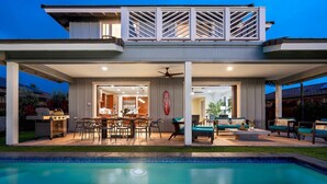 A modern two-story house with a covered patio, a pool, and a dining area. - Holua Kai #26: Luxury Fairway Front Villa w/ Pool, Spa, Lanai, AC & Ocean Views (Kailua-Kona)
