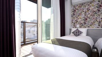 Ein Hotelzimmer mit einem großen Bett, Blick durch eine Schiebetür und floralem Wandpapier.