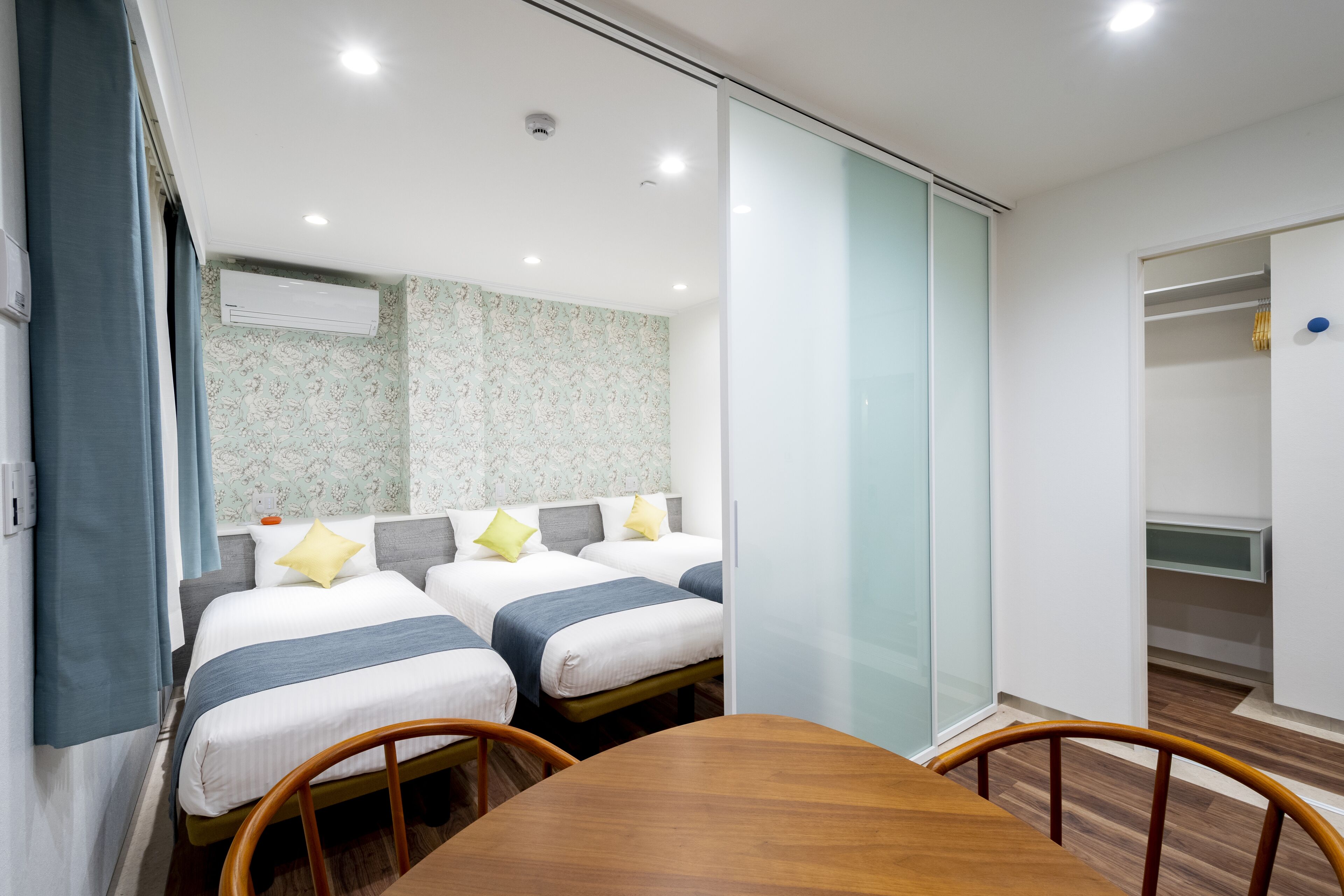 A hotel room with two beds, a wooden table, and a sliding door closet.