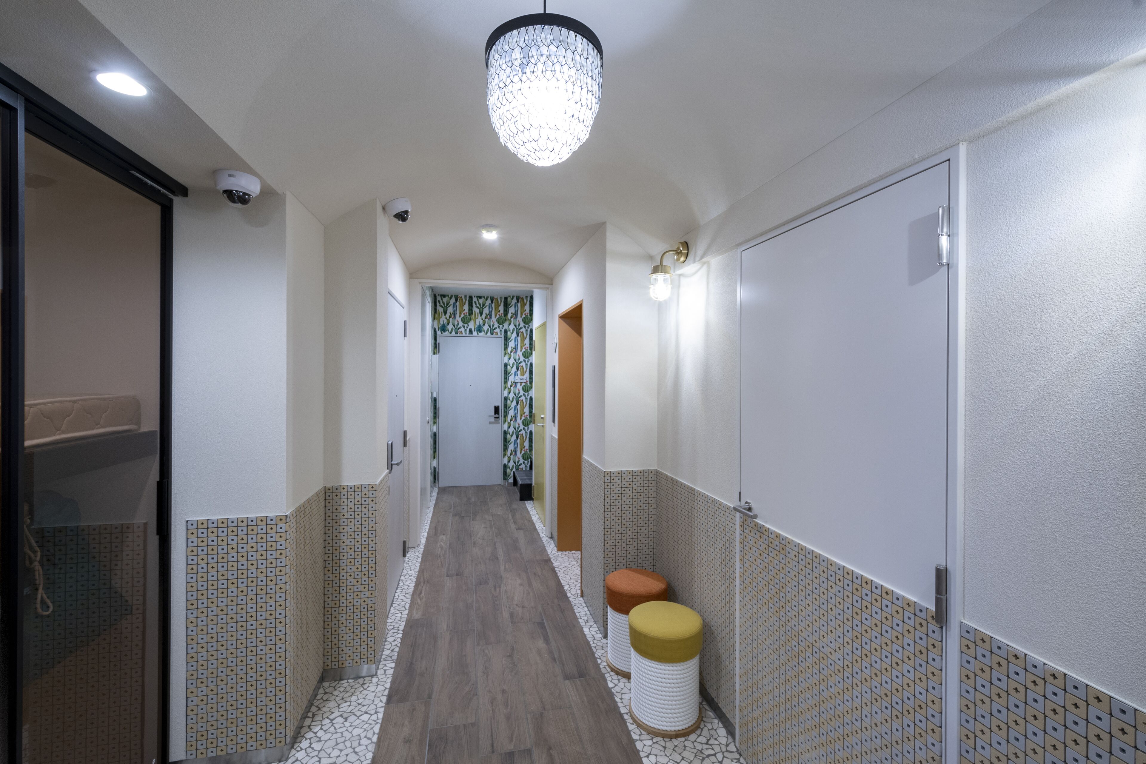 A hallway with patterned walls, a wooden floor, and a ceiling light fixture.