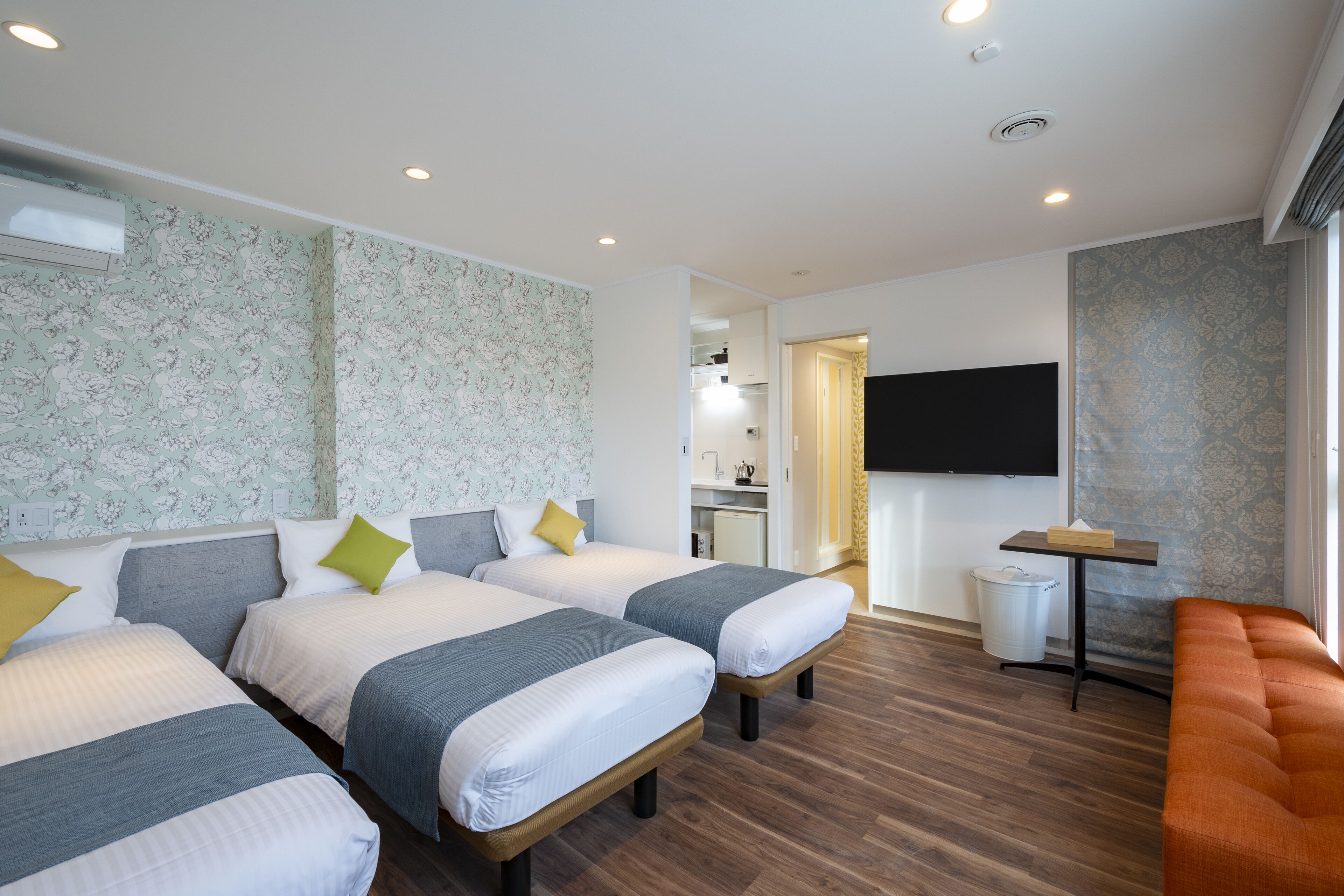 A hotel room with two beds, a TV, a small table, and a sofa.