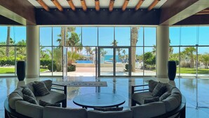 A spacious indoor area with a large glass wall offering a view of a pool and palm trees.