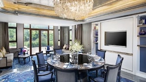 A spacious dining area with a large chandelier, round table, and blue chairs.