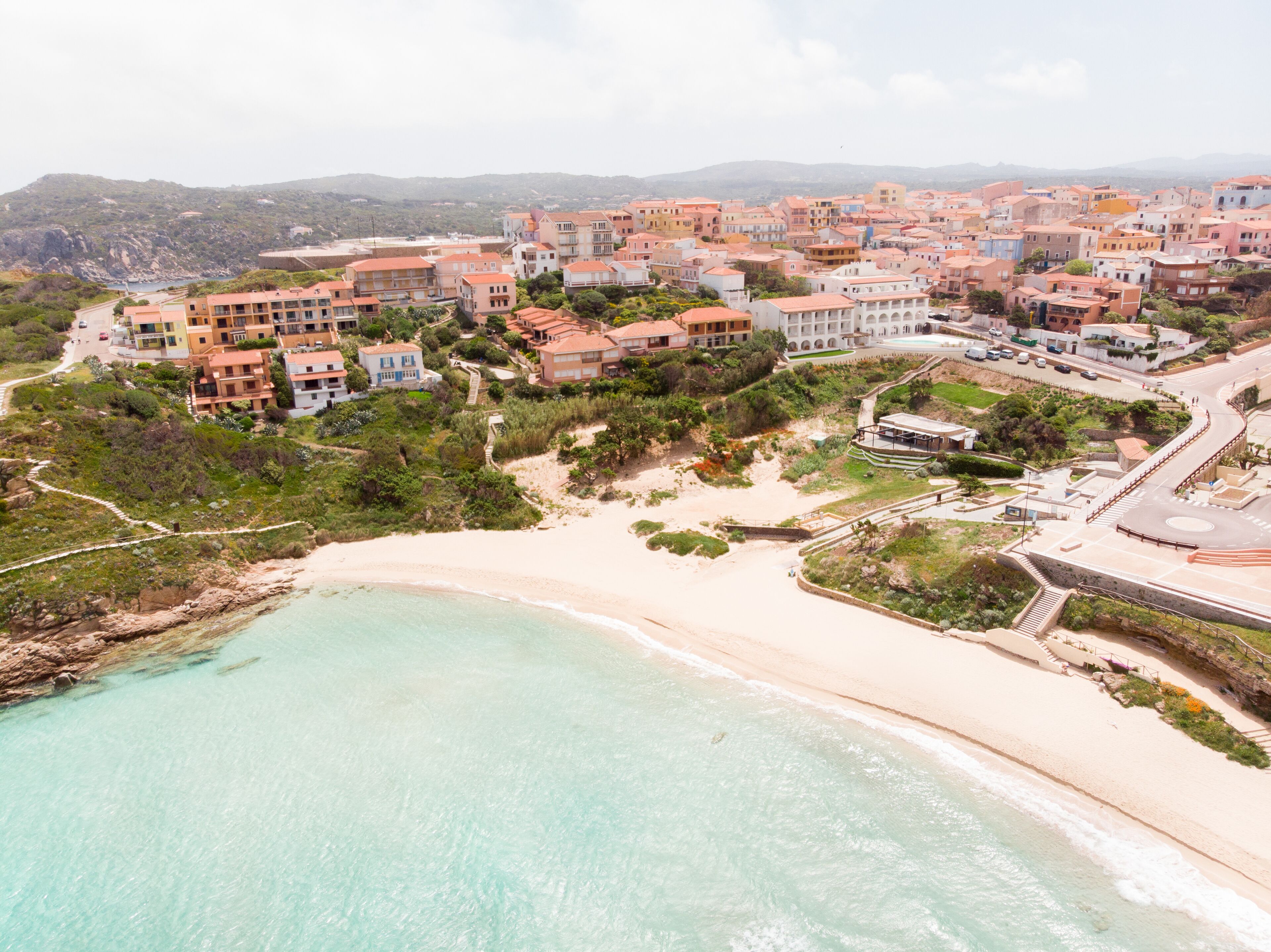 An aerial view of a coastal town with buildings, a beach, and a road.