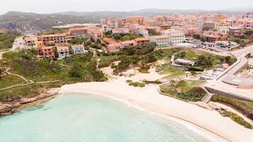 An aerial view of a coastal town with buildings, a beach, and a road.