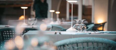 A restaurant setting with tables set for dining, featuring clear glassware and candle holders.