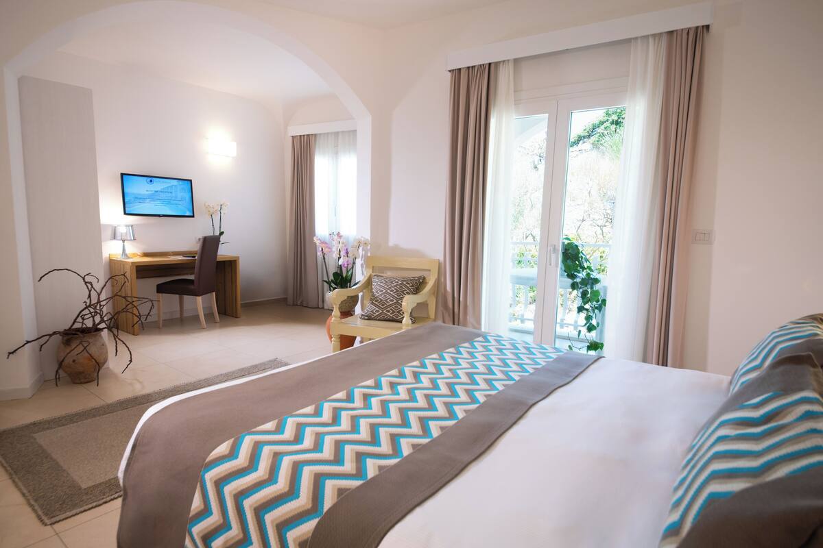 A hotel room with a bed, a desk, a chair, and a television.