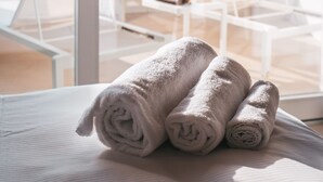 Un balcón con sillones blancos y una mesa con toallas enrolladas.