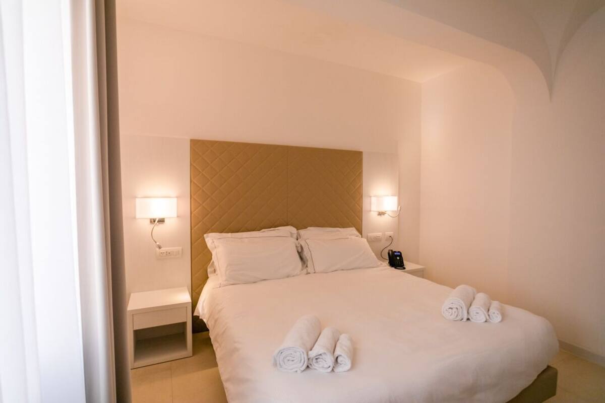 A hotel room with a large bed, two bedside tables, and a headboard.