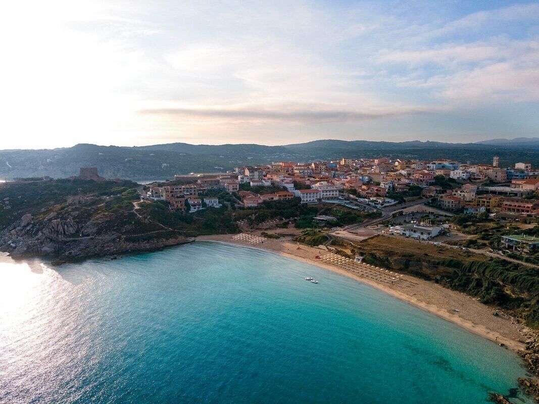 A coastal town with a beach, buildings, and a prominent tower.