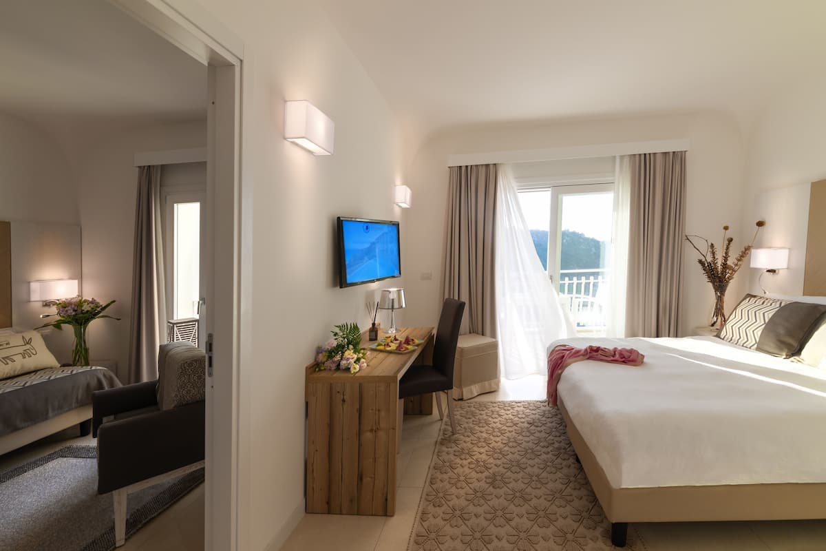 A hotel room with a bed, a desk with a chair, a television, and a window with curtains.