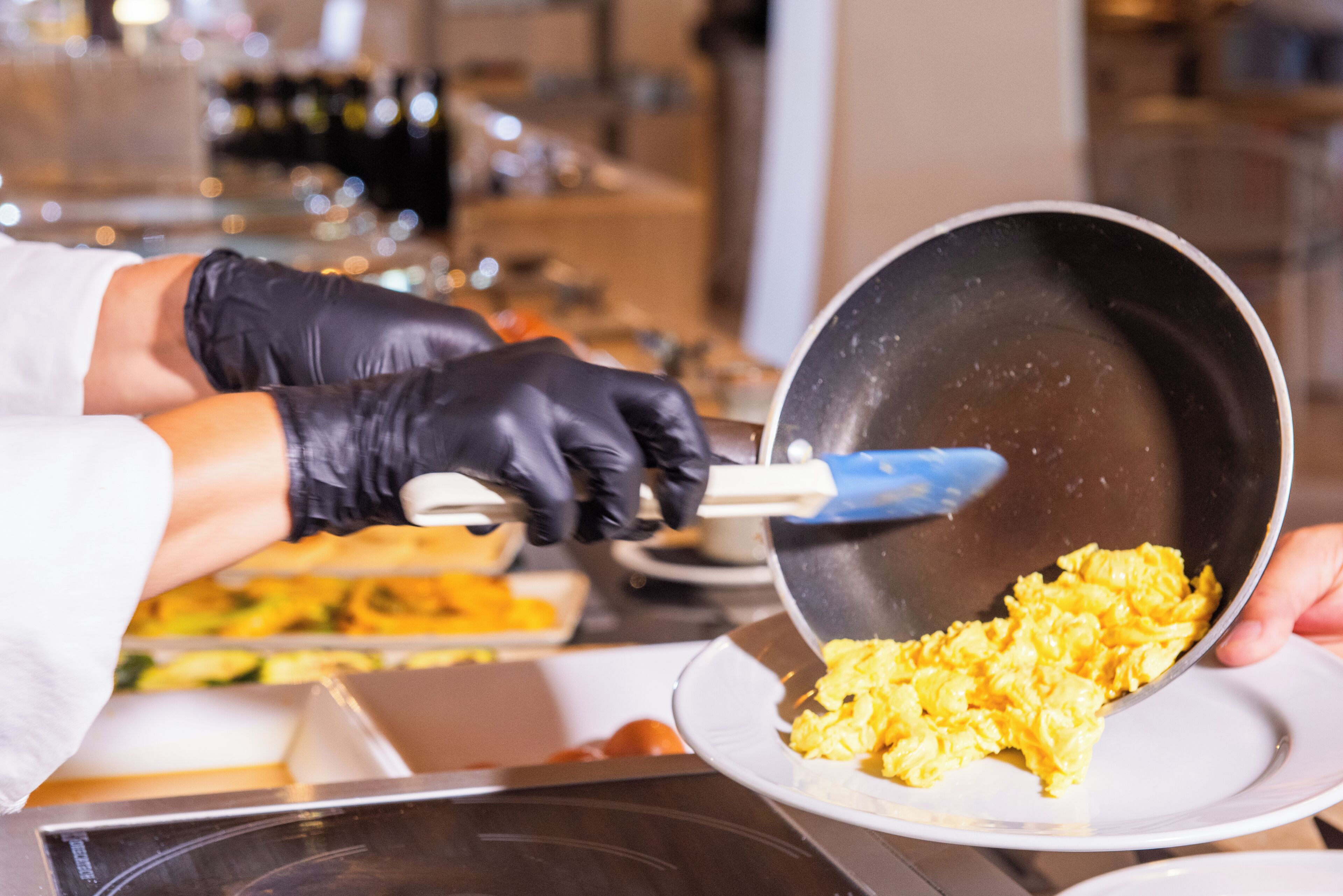 Una persona sirve huevos revueltos en un plato.
