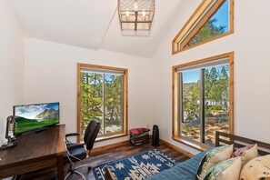 Una habitación con escritorio, silla y ventanas amplias que ofrecen vistas al exterior.