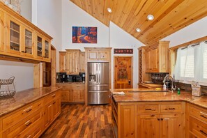 Una cocina con armarios de madera, un refrigerador de acero inoxidable y techo de madera.