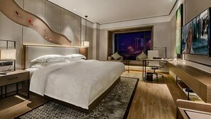 Una habitación de hotel moderna con una cama grande, un escritorio y un televisor.