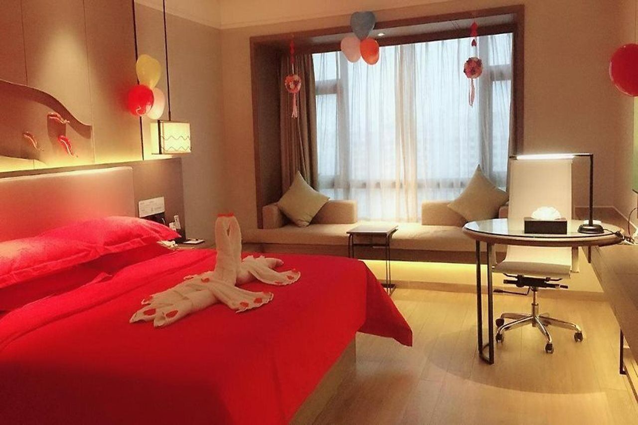 Habitació d'hotel amb un llit gran, un sofà, una taula petita i un escriptori.