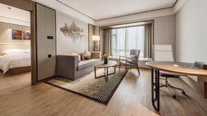 Una habitación de hotel moderna con cama, sofá, escritorio y un ventanal grande.