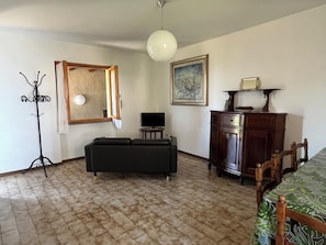 Un salon comprenant un canapé, un téléviseur, un meuble en bois, un porte-manteau et un tableau accroché au mur.