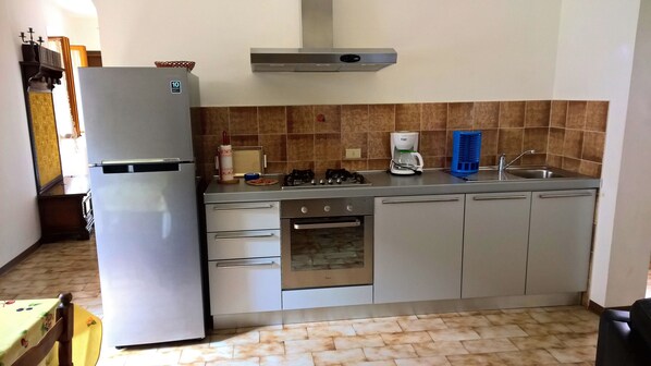 A compact kitchen with a refrigerator, stove, oven, and sink.