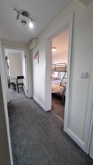 A hallway leading to a bedroom with bunk beds, a desk, and a chair. - Beachside Home - Sleeps 5, Garden, Parking & Pets (Skegness)