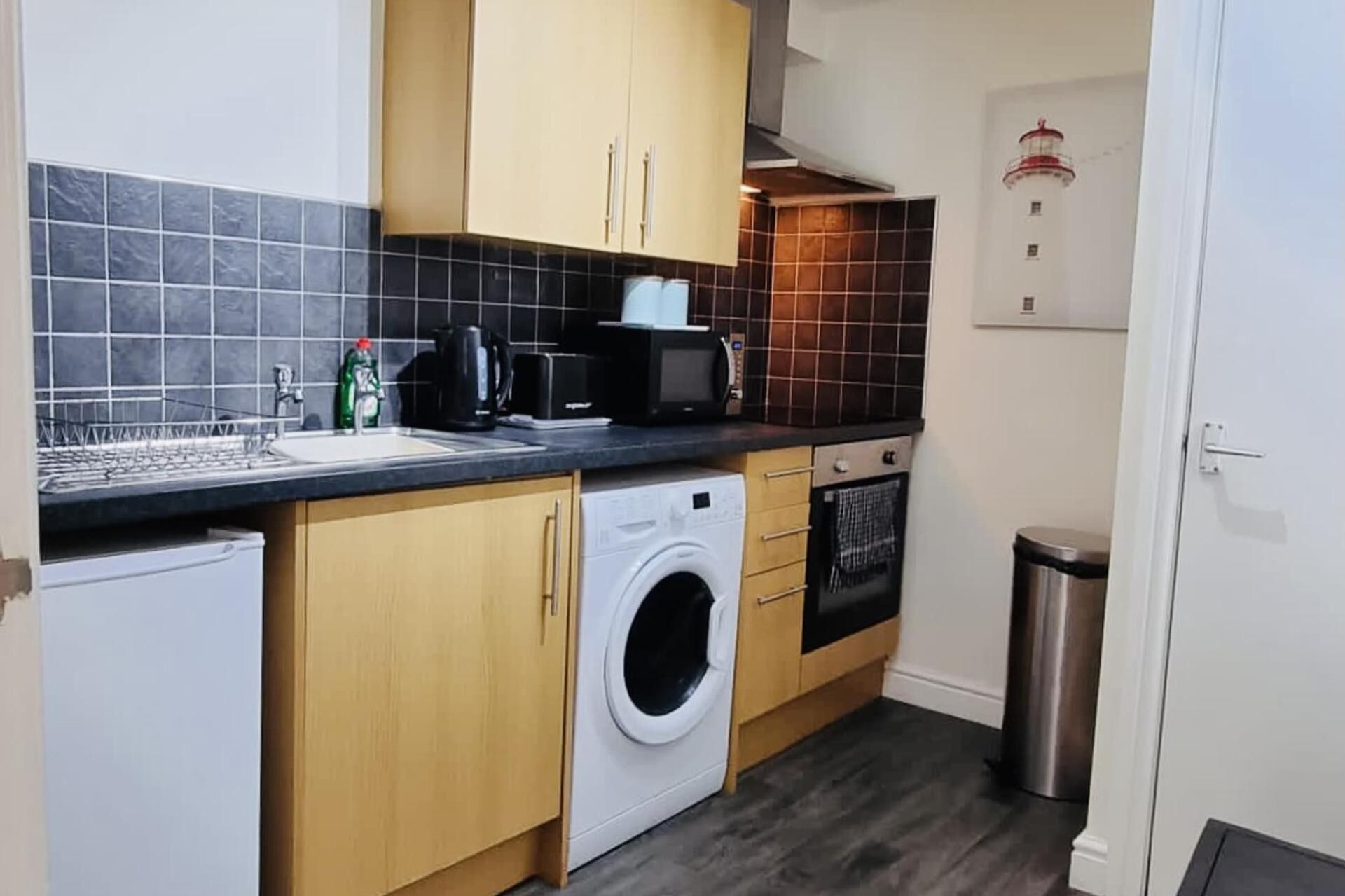 A compact kitchen with a washing machine, a microwave, and a sink.