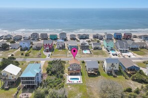 Un quartier résidentiel avec des maisons, une piscine et une plage en arrière-plan.