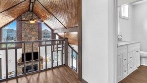 Ein modernes Interieur mit Kamin aus Stein, Holzboden und einem weißen Badezimmer mit Waschbecken und Schränken.