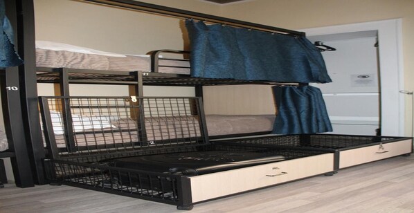 A bunk bed with a lower bunk, a mattress on the upper bunk, and a storage drawer under the lower bunk.