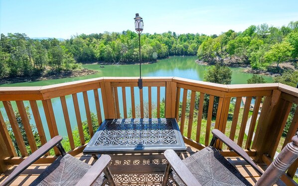 Relax on this serene outdoor space overlooking a calm body of water surrounded by lush greenery.