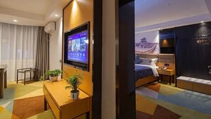 Habitación de hotel con cama, mesita de noche, televisión y vista a un edificio.