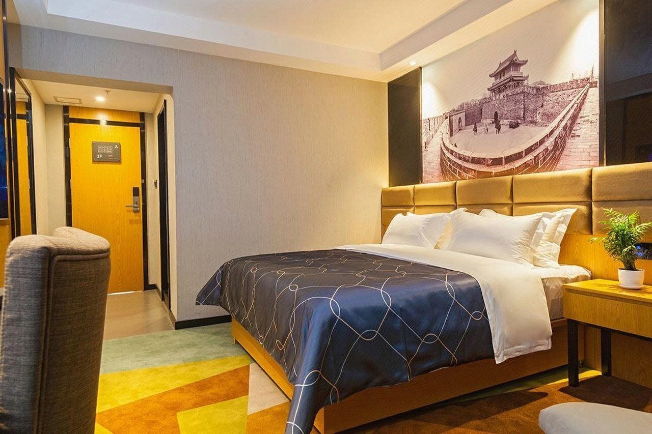 Een hotelkamer met een bed, een stoel, een nachtkastje en een aan de muur hangend schilderij.
