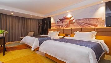 Habitación de hotel con dos camas, un mural grande de un edificio tradicional, un escritorio con una planta y una silla.