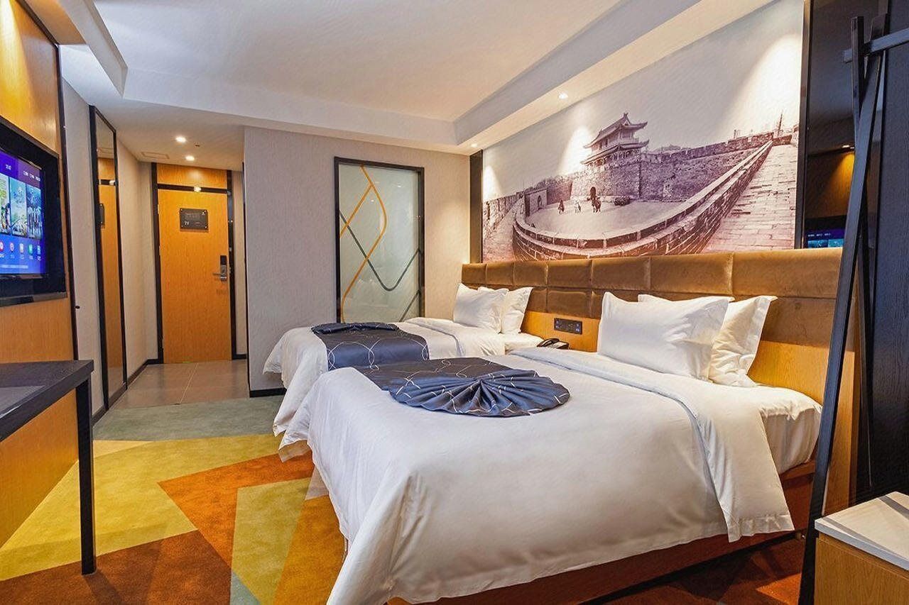 Una habitación de hotel con dos camas, televisión, un mural grande en la pared y un diseño moderno.