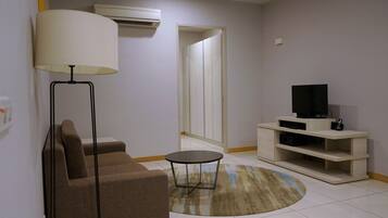 A living room with a sofa, a lamp, a TV on a stand, and a mirror.