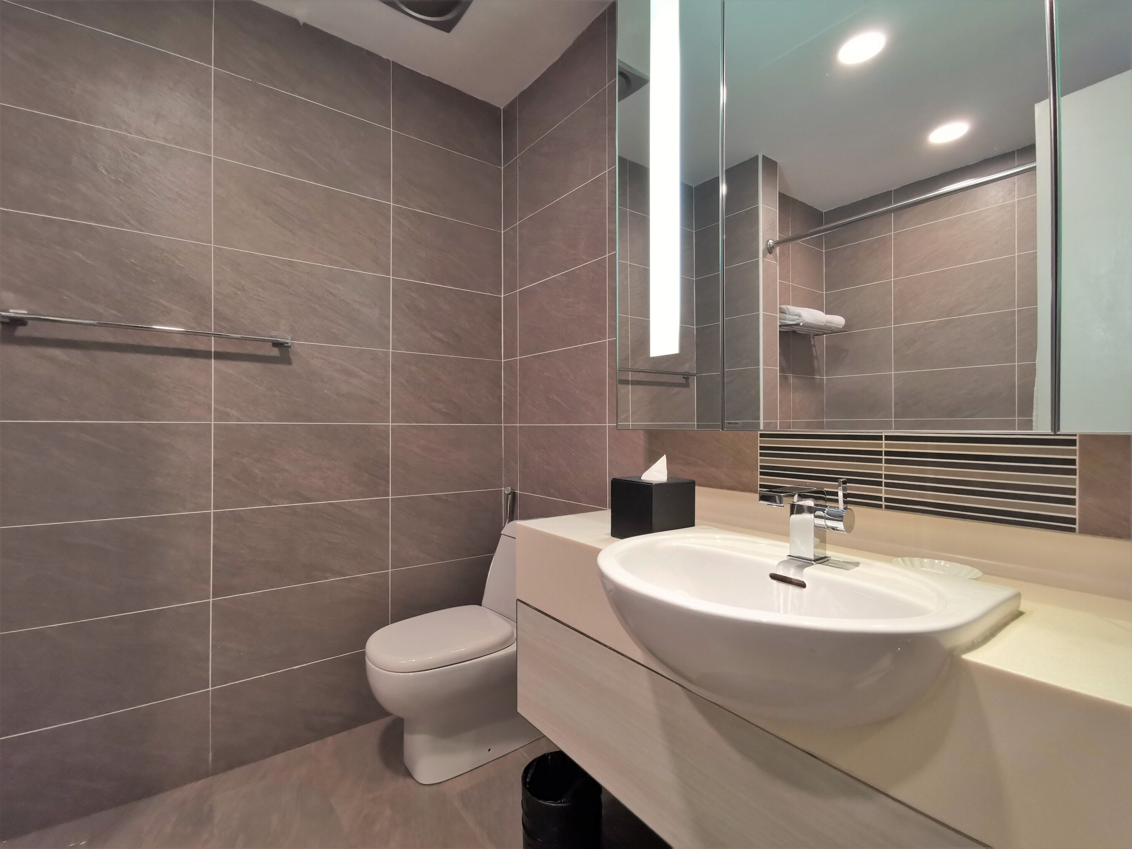 A modern bathroom with a toilet, sink, and glass shower enclosure.