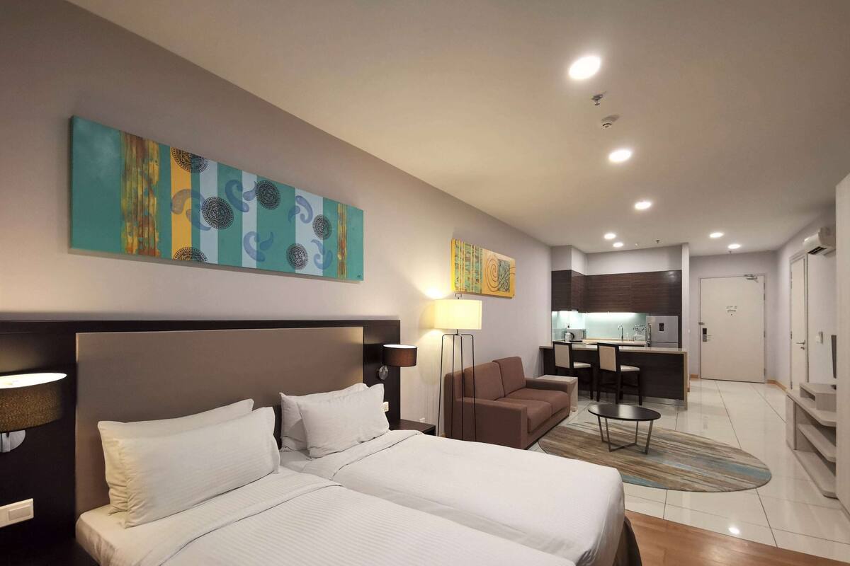 Una habitación de hotel con una cama grande, un escritorio, un sofá y una kitchenette.