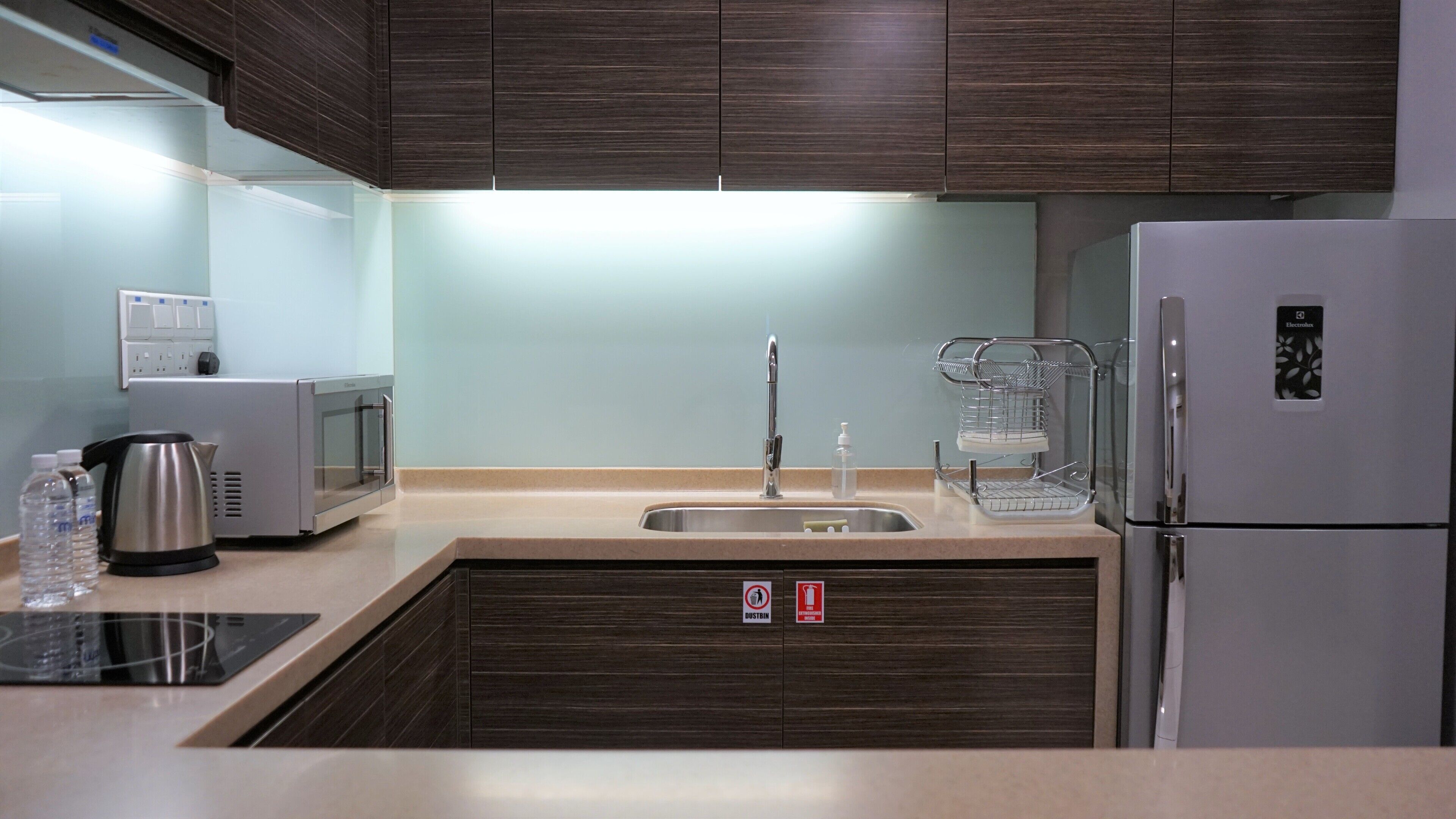 A modern kitchen with a stainless steel sink, a kettle, a microwave, and a refrigerator.