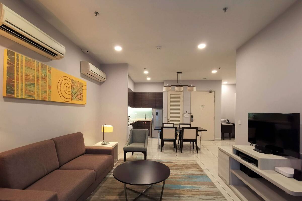 Una sala de estar moderna con un sofá, una mesa de centro, un televisor y un comedor con sillas y una mesa.