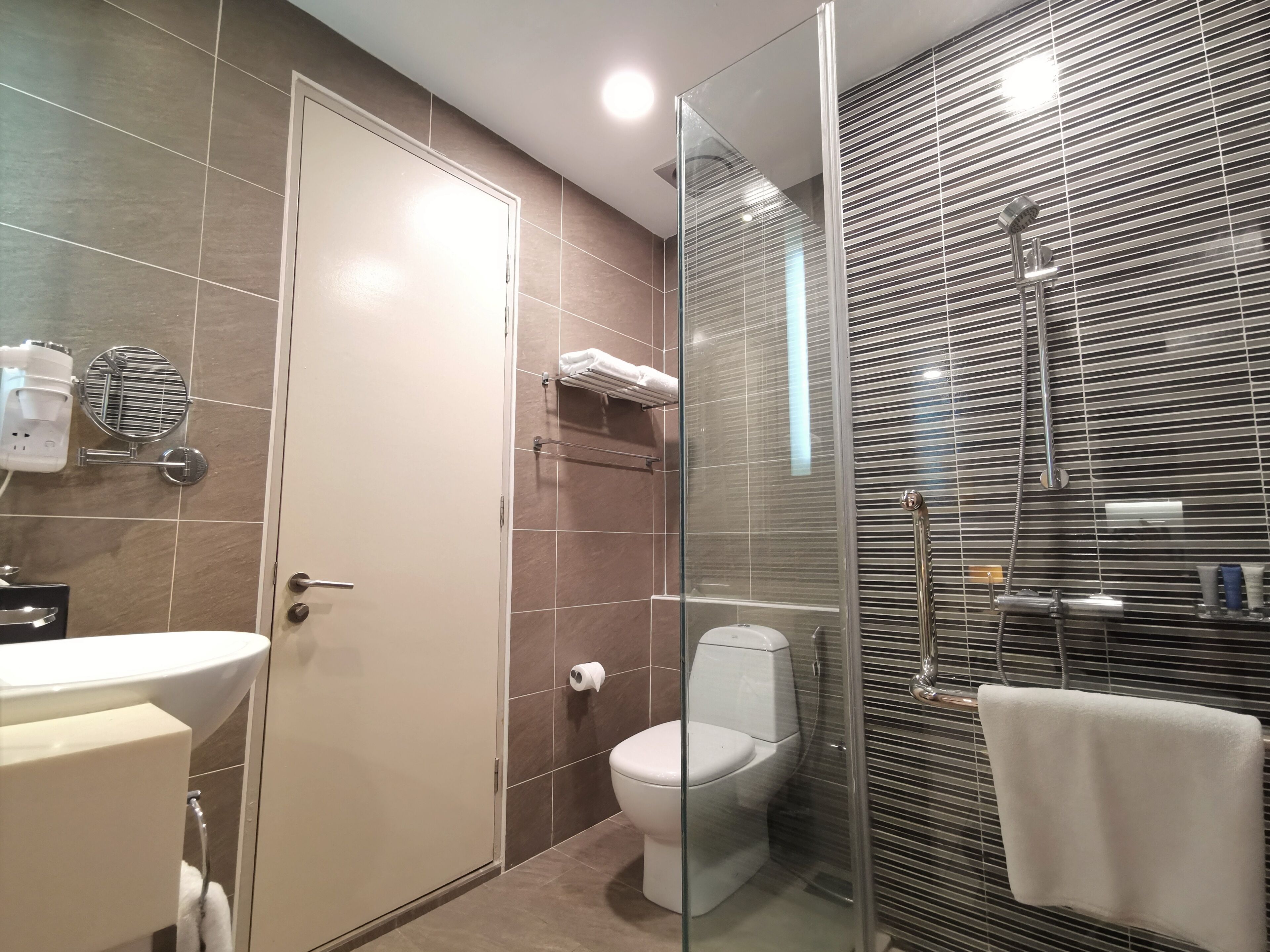 Une salle de bain moderne dotée d’une douche à parois de verre, de toilettes et d’un lavabo.