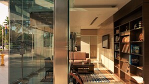 Un interior moderno con una pared de vidrio, un sofá, una mesa de centro y una estantería.