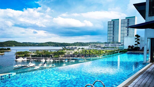 Una piscina con vistas a un puerto deportivo y edificios al fondo.