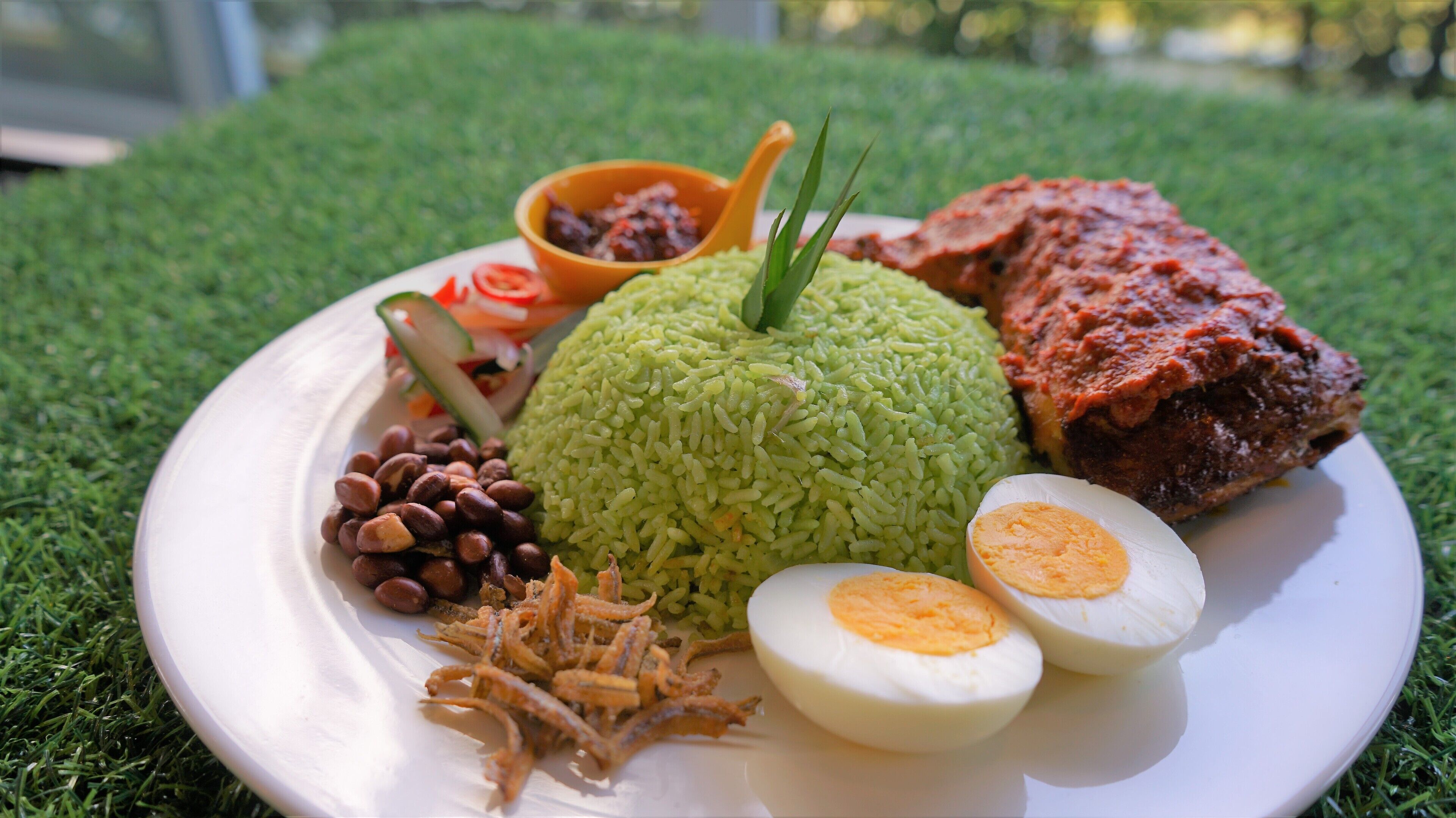 A plate of food with rice, beans, eggs, and a meat dish on a white plate.