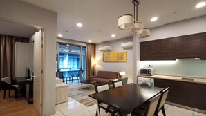 Una habitación de hotel moderna con comedor, kitchenette y balcón con vistas.